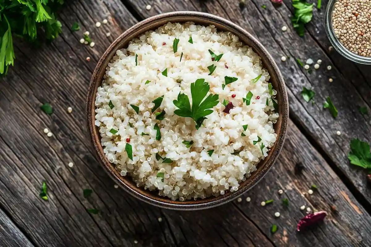 Bowl of cooked quinoa rice with raw seeds and herbs.